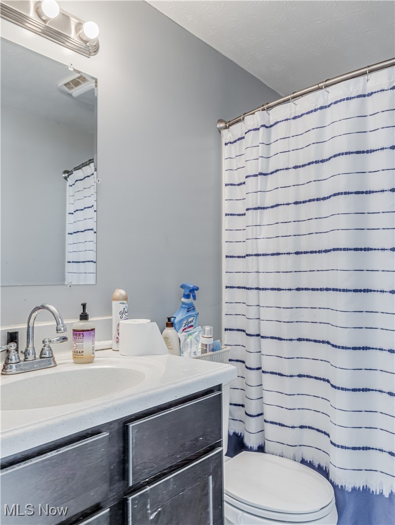 1119 Chaparrel Road Southwest Hartville, OH 44632 - Photo 8 of 23 Bathroom with a shower with curtain, vanity, toilet, and a textured ceiling