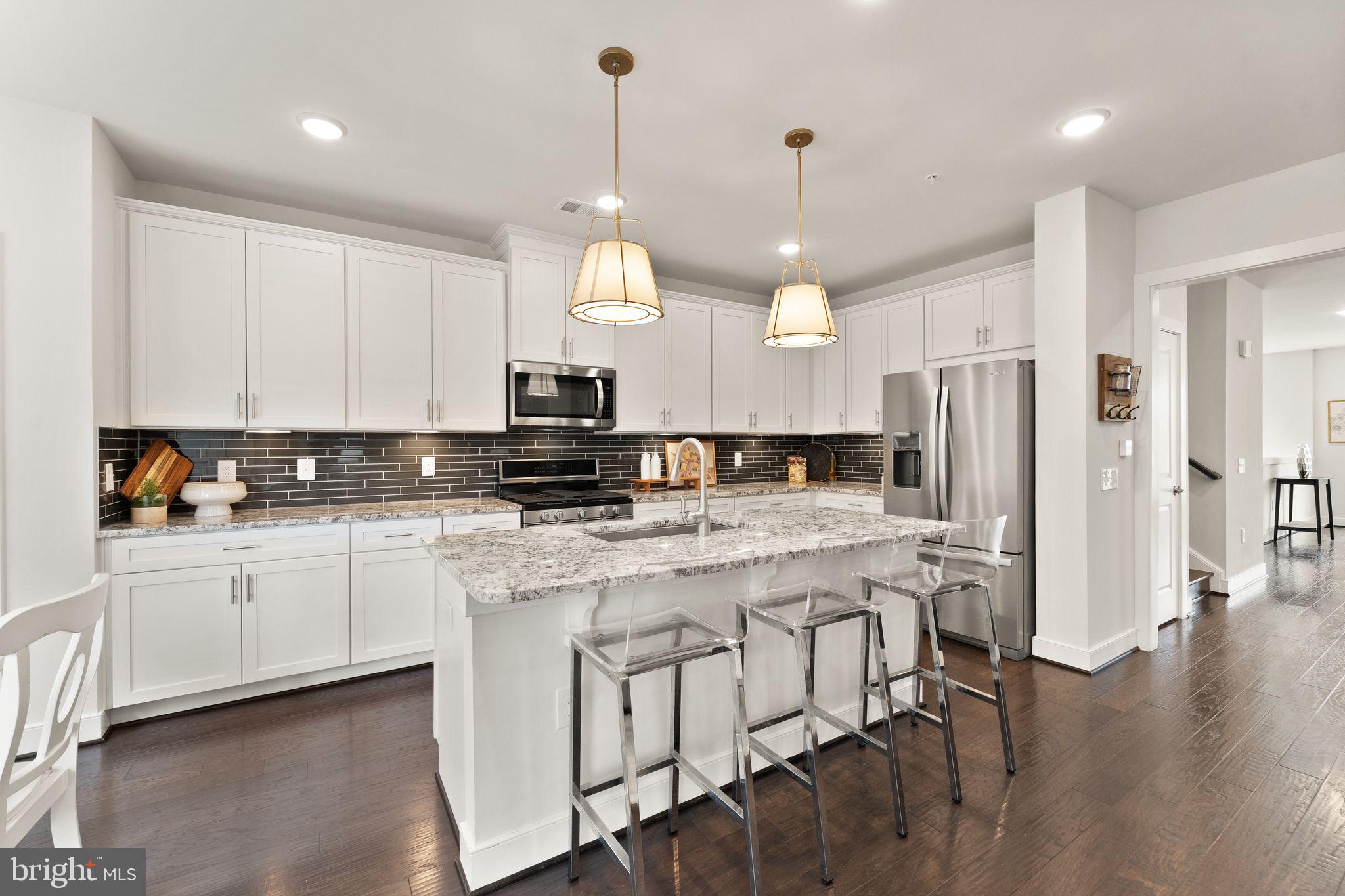 1867 Michael Faraday Drive, Unit 4 Reston, VA 20190 - Photo 19 of 53 a kitchen with stainless steel appliances granite countertop a stove a sink a refrigerator and white cabinets with wooden floor