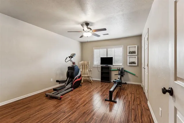 a view of a room with gym equipment and wooden floor