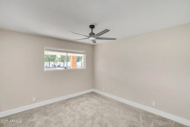 an empty room with a window and a ceiling fan