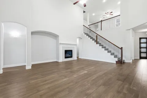 a view of an empty room with wooden floor and a fireplace
