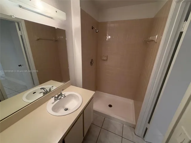 a bathroom with a sink shower and a mirror