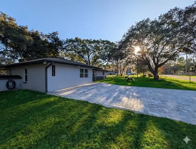 a view of a yard in front of a house with large tree