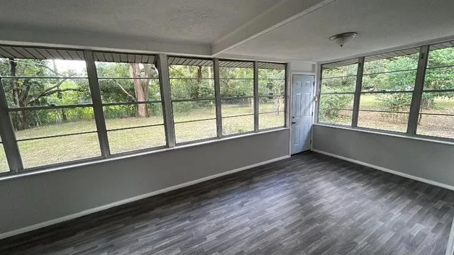 a backyard of a house with table and chairs potted plants and a large tree