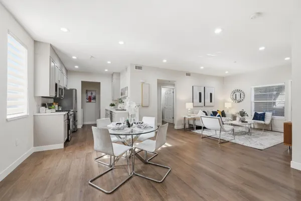 a living room with furniture kitchen view and a wooden floor