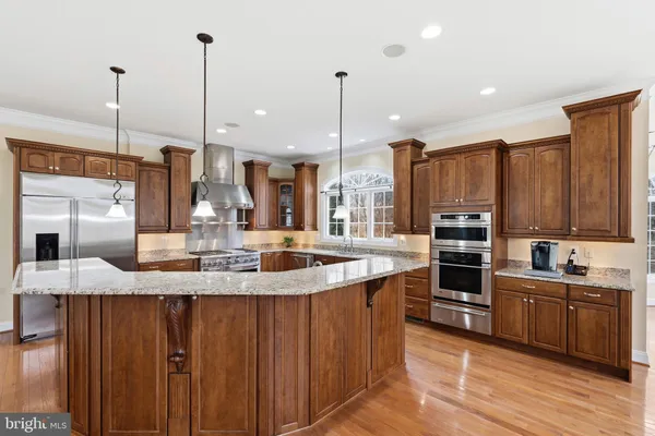 a kitchen with kitchen island granite countertop a sink appliances and cabinets