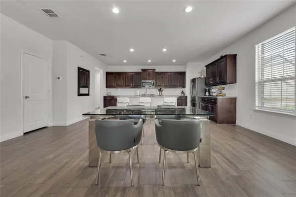 a kitchen with stainless steel appliances granite countertop a stove top oven a sink dishwasher a dining table and chairs with wooden floor
