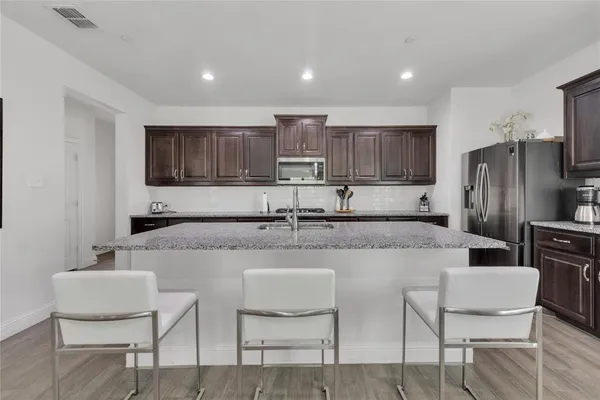 a kitchen with stainless steel appliances granite countertop a sink and a refrigerator