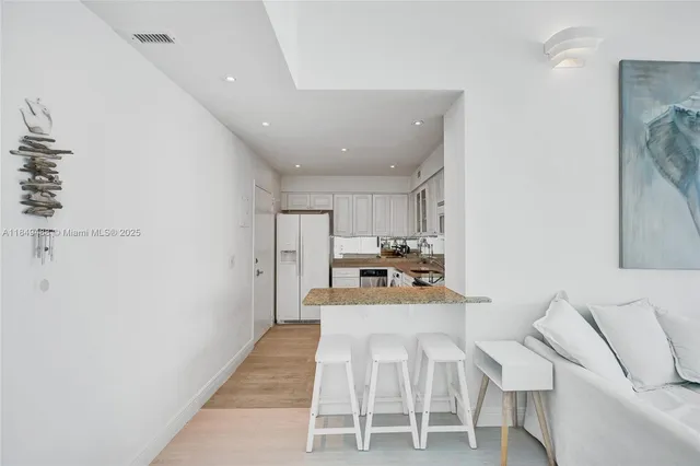 a living room with stainless steel appliances furniture a rug and a kitchen view
