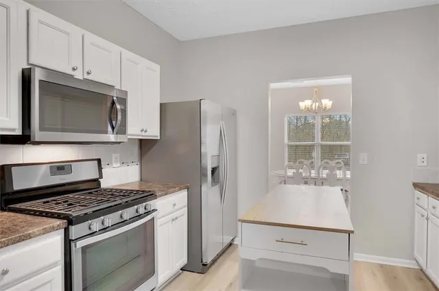 a kitchen with stainless steel appliances granite countertop a stove a refrigerator and a microwave