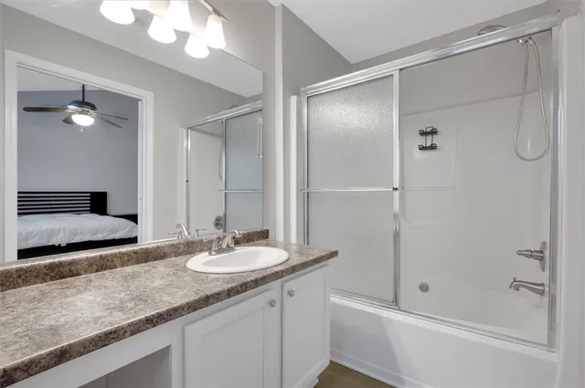 a bathroom with a granite countertop sink a mirror and shower