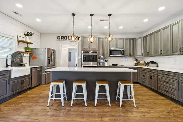 a large kitchen with stainless steel appliances lots of counter space and wooden floor