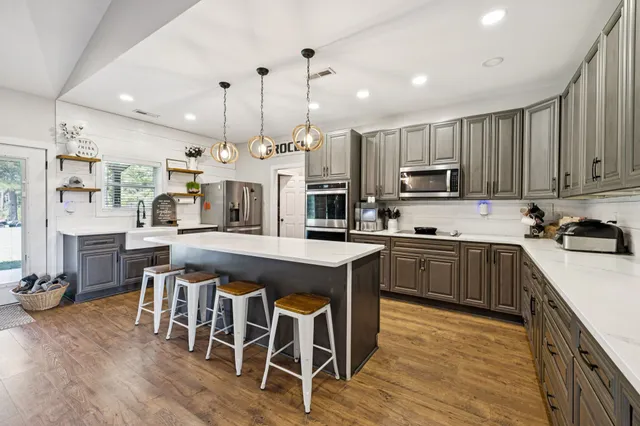 a large kitchen with kitchen island a large counter space a sink appliances and cabinets