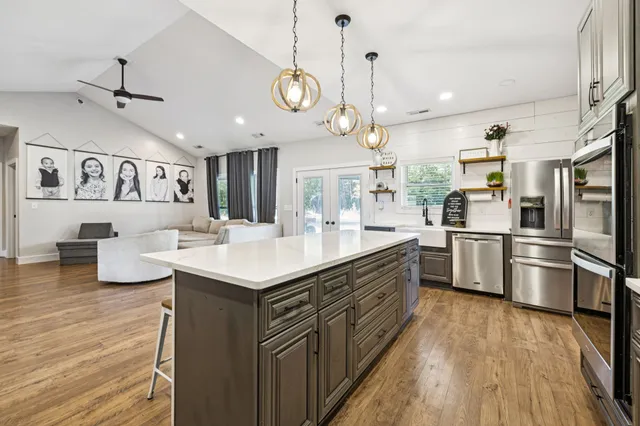 a large kitchen with kitchen island a large counter space a sink appliances and cabinets