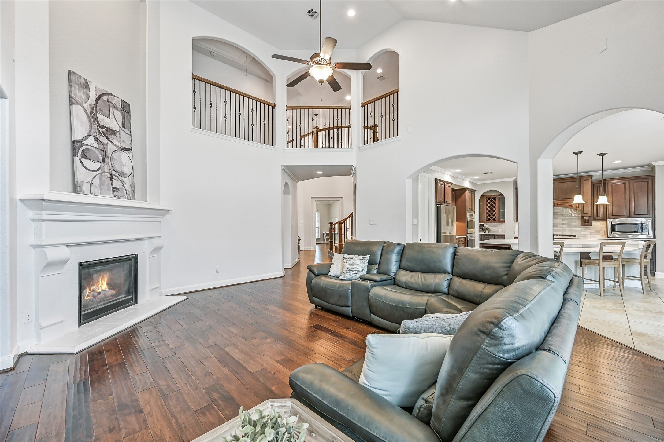 1008 Point Isabel Lane Friendswood, TX 77546 - Photo 21 of 50 Continue into the two story family room featuring engineered wood flooring, a soaring 18-foot ceiling, and open sightlines to the upper level. The space is anchored by a cast stone gas log fireplace topped by an inset art niche.