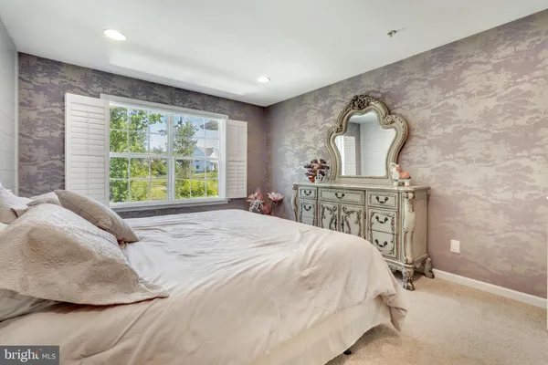 a bed sitting in a spacious bedroom next to a window