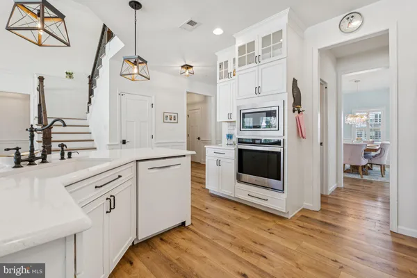 a kitchen with stainless steel appliances white cabinets and wooden floors