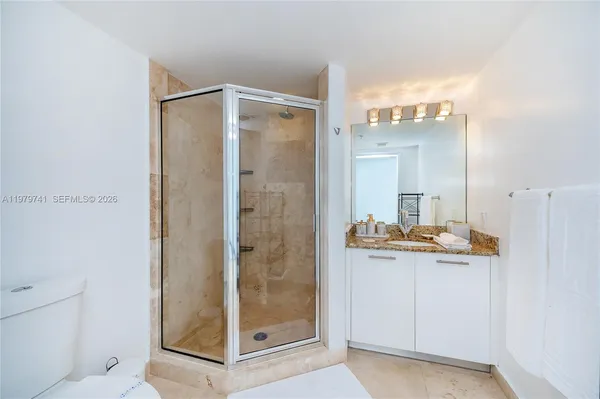a bathroom with a granite countertop shower a mirror and a sink