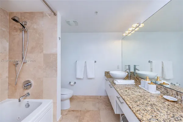 a bathroom with a granite countertop sink a toilet and shower