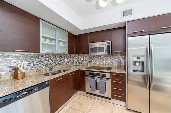 a kitchen with stainless steel appliances granite countertop a sink and a refrigerator