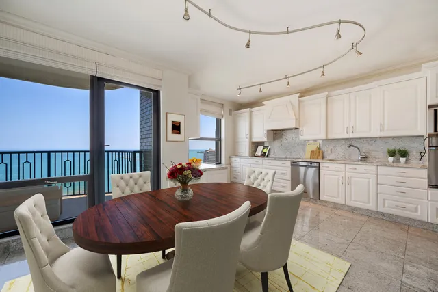 a kitchen with stainless steel appliances granite countertop a sink a stove a refrigerator a dining table and chairs with wooden floor