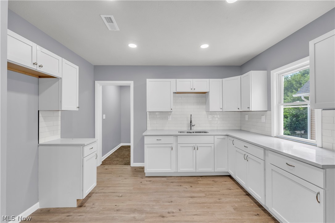 3925 Riverside Avenue Cleveland, OH 44109 - Photo 28 of 46 Kitchen featuring white cabinetry, light-toned countertops, subway tile backsplash, wood-finish flooring, and recessed lighting