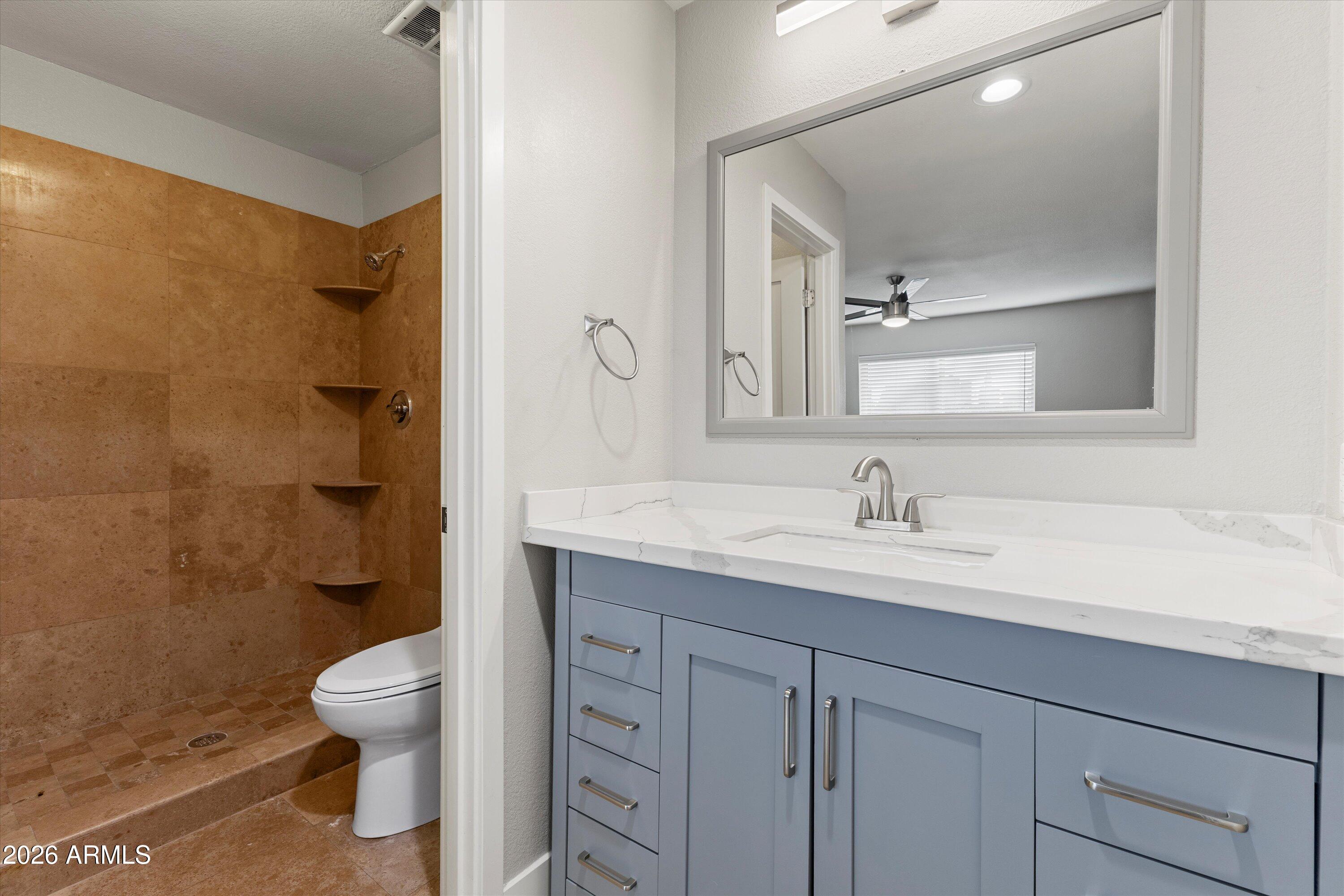 5525 East Thomas Road, Unit L1 Phoenix, AZ 85018 - Photo 30 of 33 a bathroom with a granite countertop sink a toilet a mirror and shower
