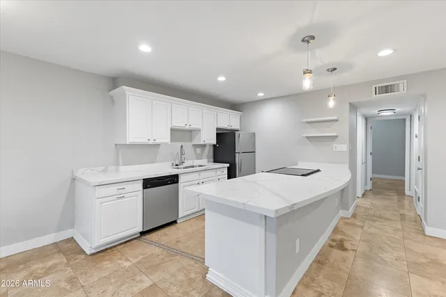 a large kitchen with stainless steel appliances kitchen island a sink dishwasher a stove and a refrigerator with wooden floor