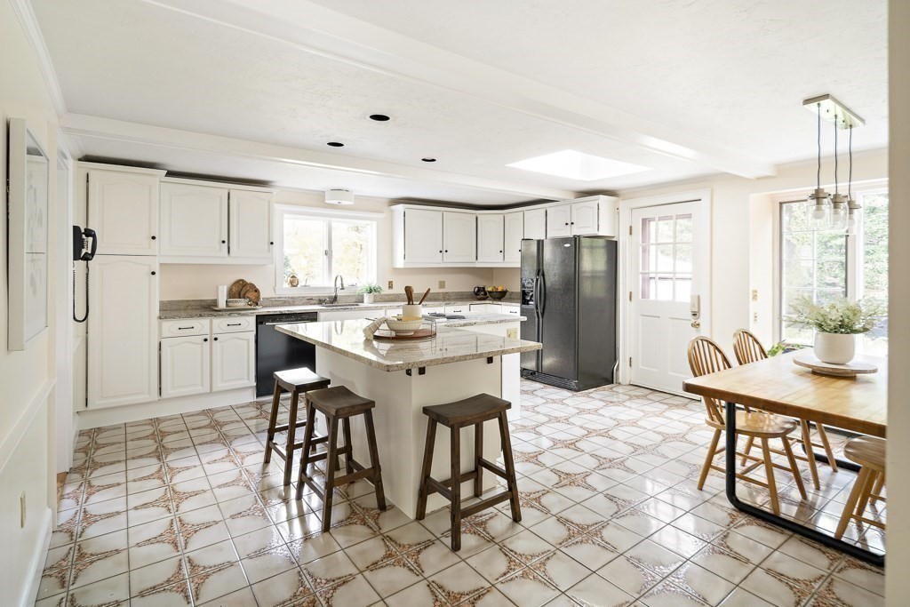 20 Stowell Road Winchester, MA 01890 - Photo 14 of 34 a kitchen with stainless steel appliances kitchen island granite countertop a table chairs and a refrigerator
