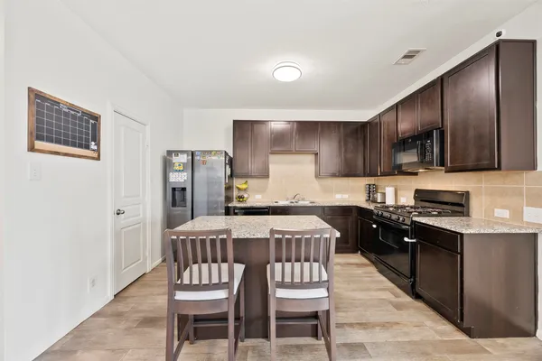 a kitchen with stainless steel appliances granite countertop a kitchen island hardwood floor sink and stove
