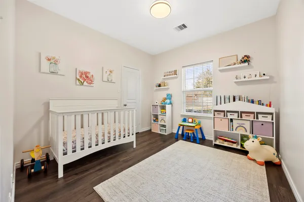 a bedroom with baby crib and a wooden floor