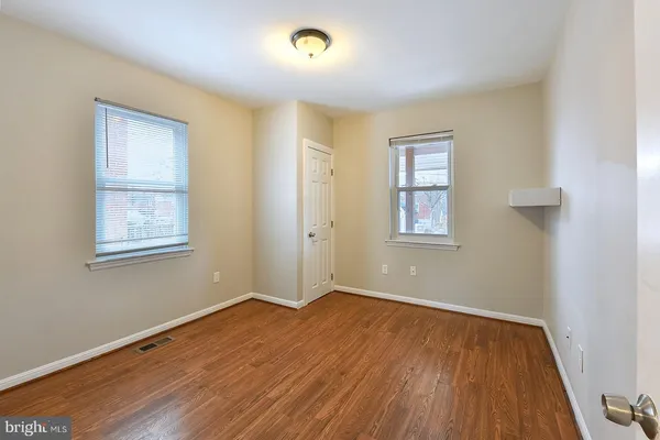 an empty room with wooden floor and windows