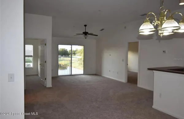 a view of a livingroom with a chandelier fan and windows