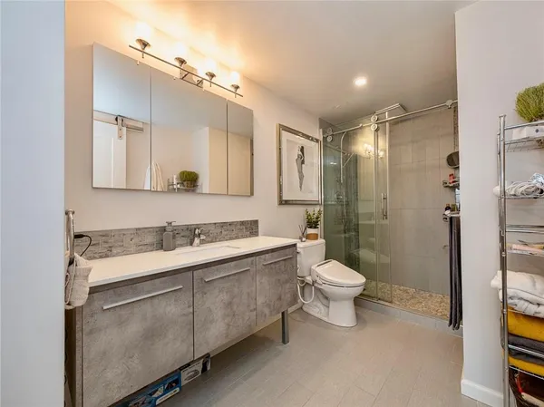 a bathroom with a double vanity sink toilet mirror and shower