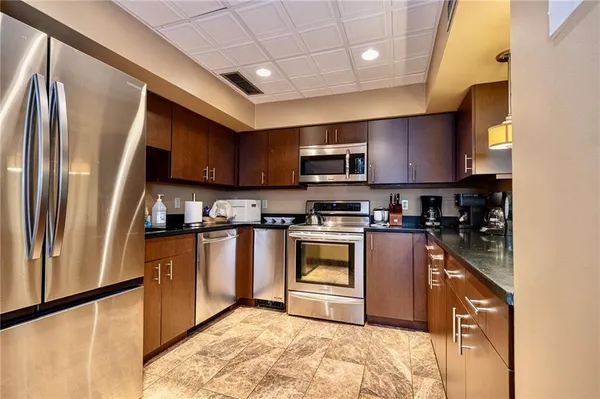 a kitchen with stainless steel appliances granite countertop a refrigerator a stove a sink a microwave oven with a dining table and chairs