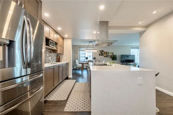 a kitchen with stainless steel appliances a refrigerator a stove a sink dishwasher and white cabinets with wooden floor