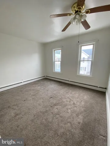 en empty room with windows and ceiling fan