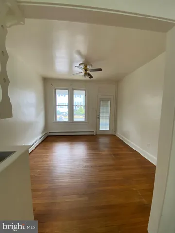 a view of empty room with wooden floor and fan