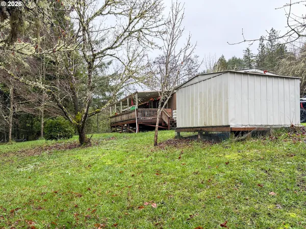a view of a backyard with wooden fence and large trees