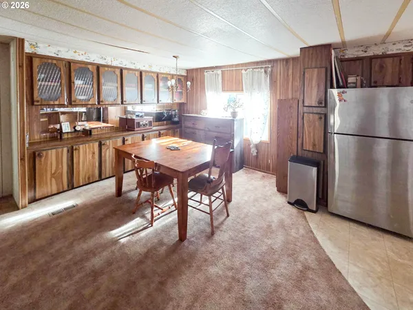 a kitchen with stainless steel appliances a refrigerator a stove a sink a dining table and chairs