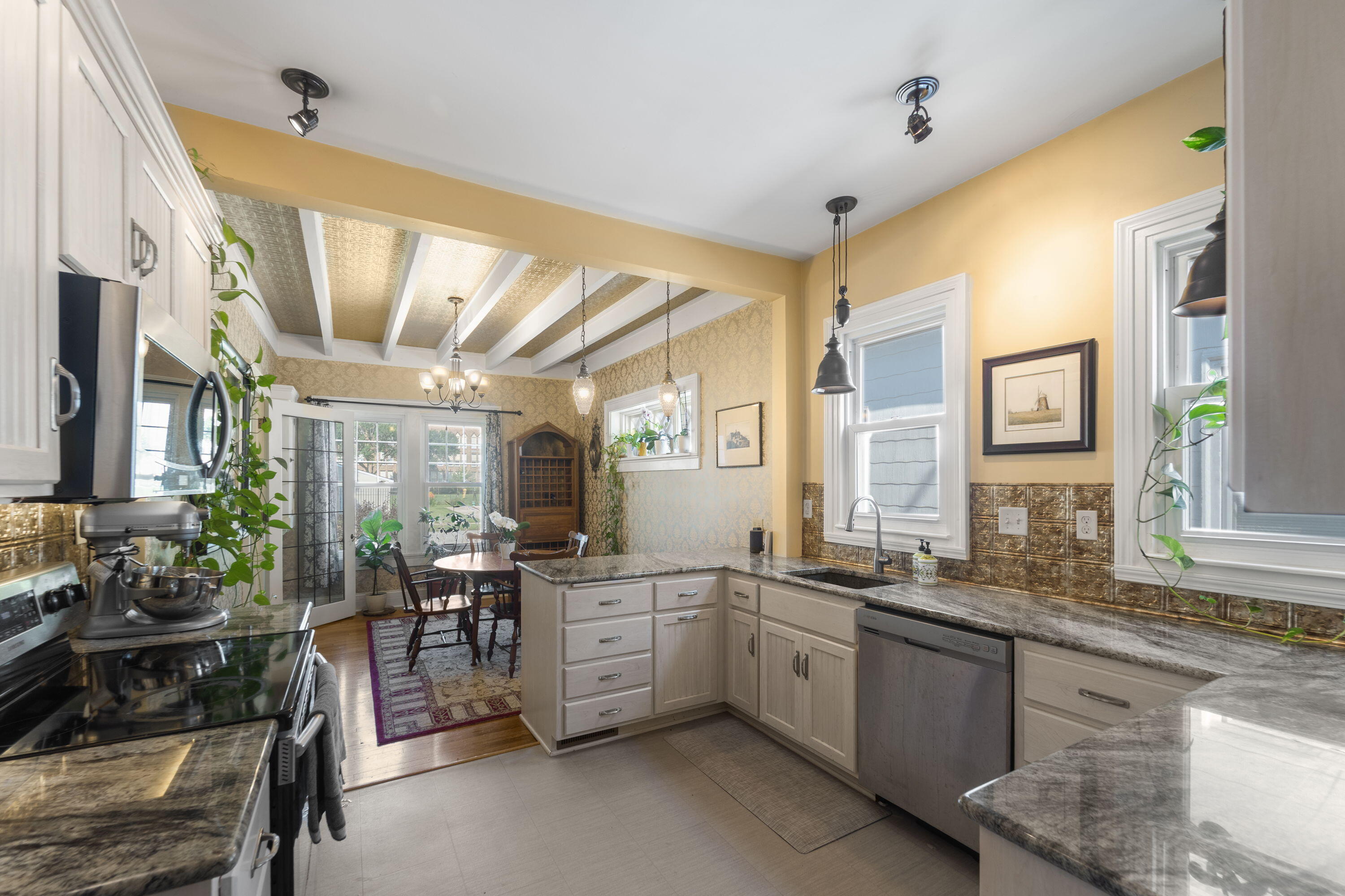 1213 College Avenue Racine, WI 53403 - Photo 9 of 31 Open-concept kitchen and dining area featuring beamed ceilings, sleek stainless steel appliances, and an abundance of natural light.