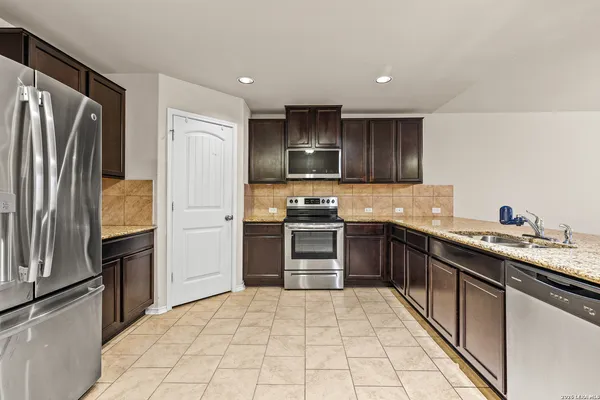 a kitchen with stainless steel appliances granite countertop a refrigerator and a stove top oven