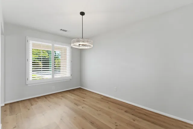a view of empty room with window and chandelier