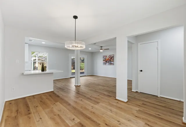 a view of an empty room with window and wooden floor