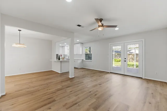 a view of an empty room with a window and wooden floor