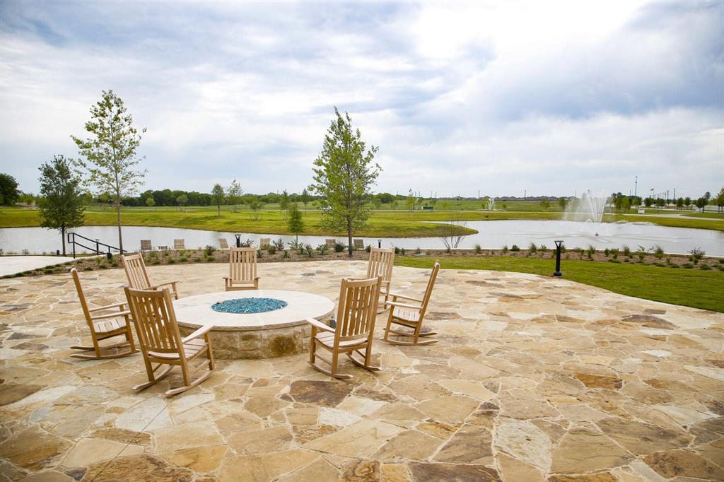 1429 Eclipse Road Aubrey, TX 76227 - Photo 36 of 37 Spacious outdoor patio area featuring flagstone paving, a built-in fire pit with blue fire glass, and several wooden rocking chairs
