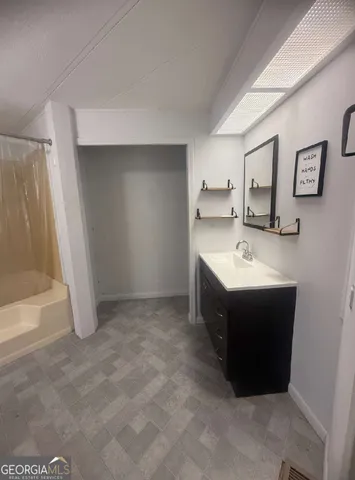 a spacious bathroom with a tub sink and mirror