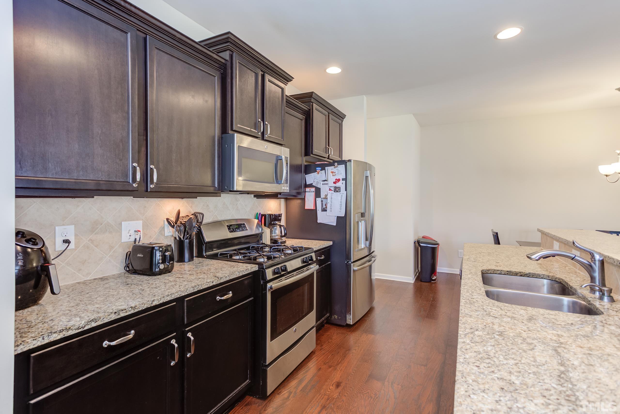 1313 Still Monument Way Raleigh, NC 27603 - Photo 13 of 35 a kitchen with stainless steel appliances granite countertop a sink stove and refrigerator