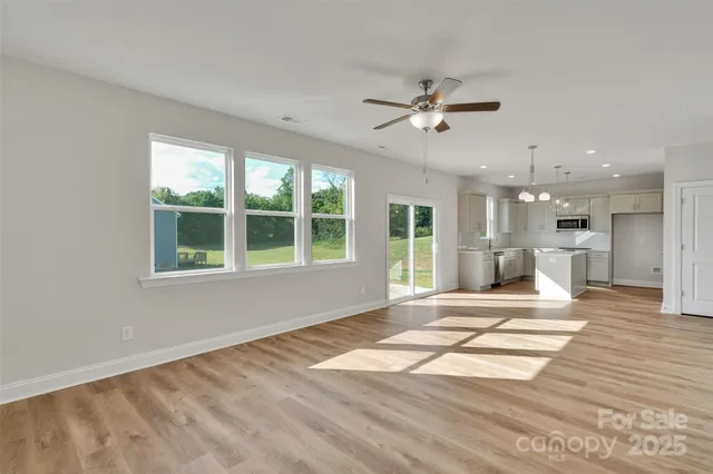 a view of an empty room with a window and a kitchen