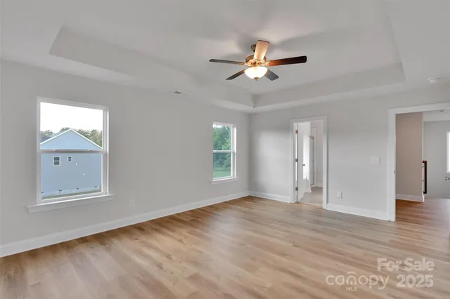 a view of an empty room with a window and wooden floor
